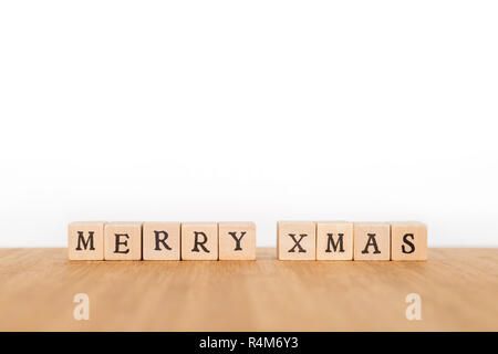 Focus on the phrase 'Merry Xmas' made of wooden block dice with letters on a wooden table. Shallow depth of field. Copy space. Stock Photo