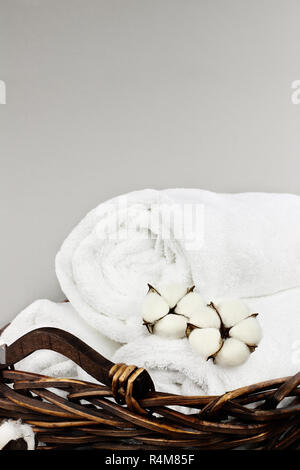 Laundry basket filled white fluffy towels, cotton flowers and a bottle of  liquid soap against a blurred grey background Stock Photo - Alamy