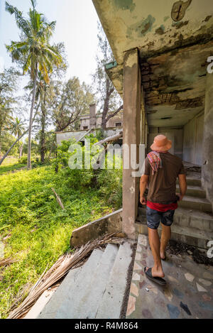 A tiorist explores the abandoned buildings of Santa Carolina Hotel on Paradise iIsland in MOzambique's Bazaruto Archipelago. Stock Photo