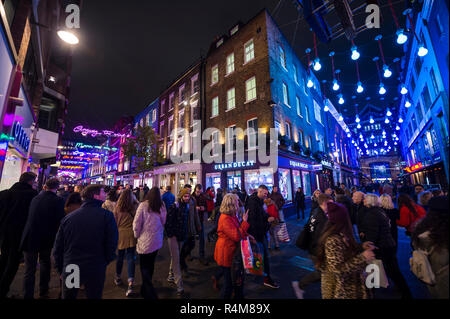 LONDON - NOVEMBER 23, 2018: Black Friday holiday shoppers admire the Bohemian Rhapsody themed Christmas lights decorating Carnaby Street Stock Photo