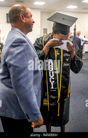 Overcome with happy emotion, an African American woman college graduate cries on a handkerchief in the company of an academic administrator before graduation ceremonies at the University of California at Irvine. Stock Photo