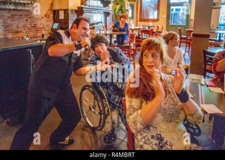 A Middle Eastern singer entertains adult and senior women at a Santa Ana, CA, pub in late afternoon sunshine. Note woman in wheelchair. Stock Photo