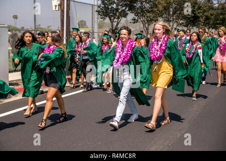 Happy high school graduates, many wearing leis, march to meet audience and family members after commencement exercises in Costa Mesa, CA. Stock Photo