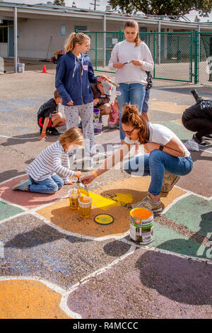 Students, parent and faculty volunteers work at repainting and restoring a map of the US in a school playground in Costa Mesa, CA. Stock Photo