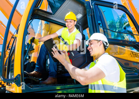 Asian construction driver discussing with engineer blueprints Stock Photo