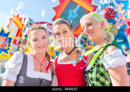 Friends visiting Bavarian fair having fun at carousel Stock Photo