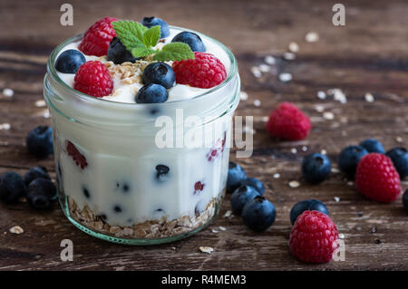 Serving of Yogurt with Whole Fresh Blueberries, Raspberries and Oatmeal on Old Rustic Wooden Table Stock Photo
