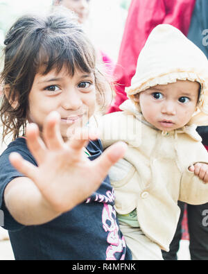 SAURAHA, NEPAL - APRIL 2015: portrait of Nepali girl with an infant in her hands in Chitwan national park. Stock Photo