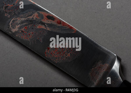 Dusted finger prints showing up as forensic eveidence on a sharp steel sharp large bladed knife with human blood stains Stock Photo