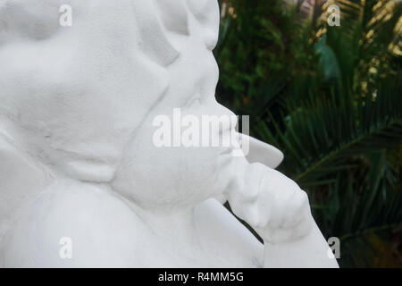 White statue of the angel against the background of palm trees Stock Photo