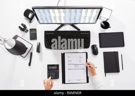 Elevated View Of A Businesswoman Calculating Invoice Stock Photo