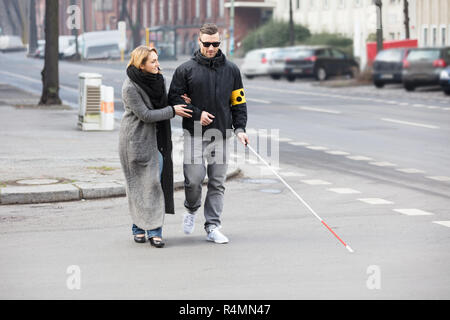 Woman Assisting Blind Man On Street Stock Photo