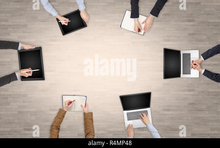 Group of people with devices in hands having desk discussion and making reports together on laptop, tablet, notebook  Stock Photo