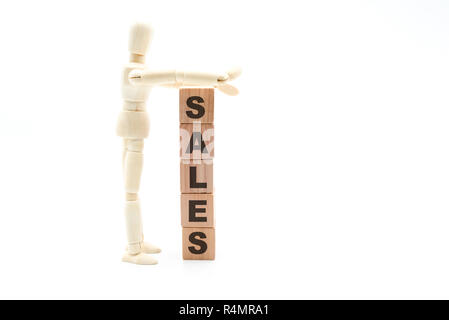 Wooden figure as businessman building Sales as tower of wood cubes, isolated on white background, minimalist concept Stock Photo