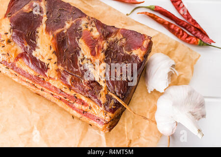 https://l450v.alamy.com/450v/r4mt5m/block-of-tasty-smoked-bacon-and-garlic-with-chili-pepper-on-wrapping-paper-top-view-r4mt5m.jpg