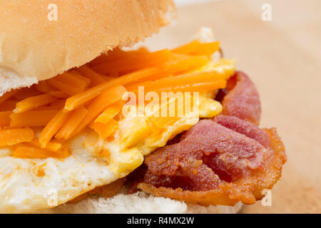 Smoked back bacon produced in the EU and bought from a UK supermarket that has been fried and placed on a bread roll with a fried egg and a sprinkling Stock Photo