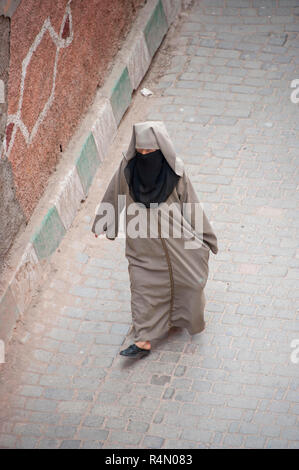 18-04-11. Marrakech, Morocco.  A street scene in the medina photographed from above. A woman in traditional dress of a hajib and scarf walks down the Stock Photo