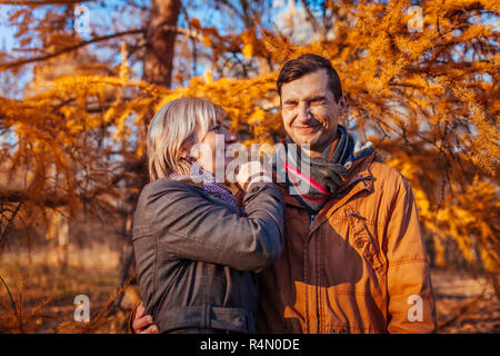 Adult son hugging and kissing his middle-aged mother in autumn park. Family values Stock Photo