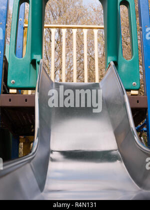 a close up shot of a metal slide in a child's playground with bark wooden chips for safety, accident, no people shining metal, dangerous and fun for children and parents Stock Photo