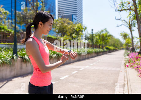 Sport Woman running with smart watch in benjakitti park Stock Photo