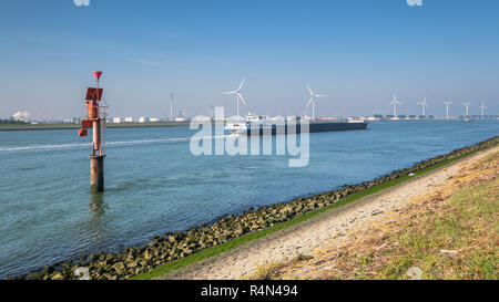 Ship sailing on the New Waterway along industries and wind turbines in the direction of the North Sea. This is the access route for large seagoing ves Stock Photo