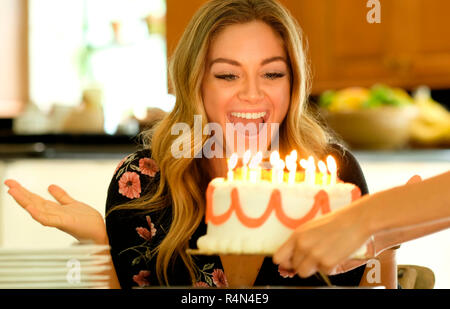 Surprised young woman receiving birthday cake Stock Photo