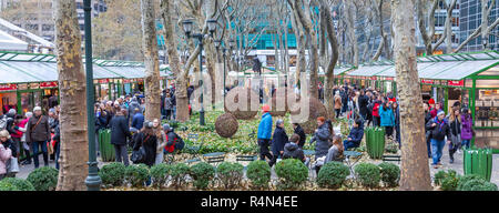 Families and friends of all ages enjoy shopping in the Christmas Village Shops in the Winter Village at Bryant Park, Manhattan, New York City. Stock Photo