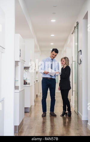 Dentist and dental nurse discussing notes in corridor Stock Photo