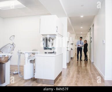 Dentist and dental nurse discussing notes in corridor Stock Photo