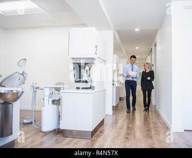 Dentist and dental nurse discussing notes in corridor Stock Photo