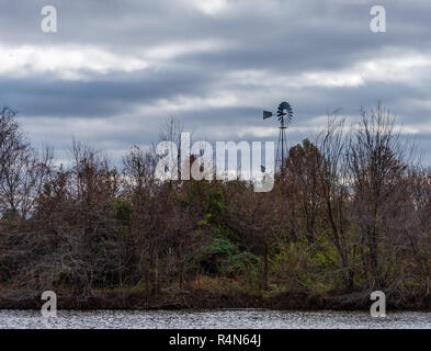 A solitary windmill stands in a field on a cold, windy and overcast  day. Stock Photo