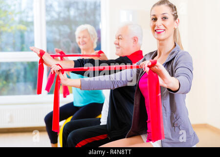 People at gym exercise with stretch band Stock Photo