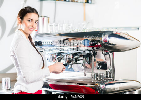 Young waitress using an automatic coffee machine Stock Photo
