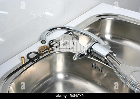 Hardware parts necessary for the installation of a faucet in a kitchen sink. Stock Photo