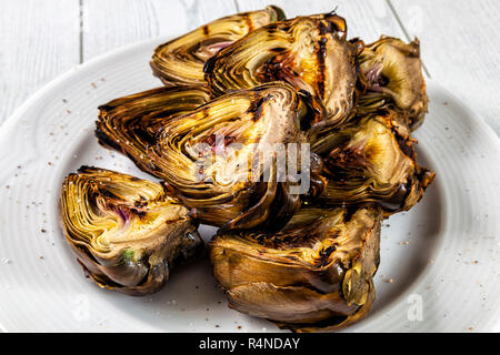 Grilled artichokes with salt and pepper on a plate. Stock Photo