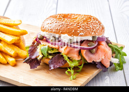 Bagel sandwich with sesame seeds and salmon. Served with french fries. Stock Photo