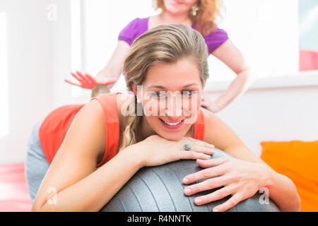 Pregnant young women getting backrub with spiky massage ball Stock Photo