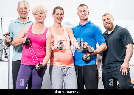 Group of people in gym with stretch bands and dumbbells Stock Photo