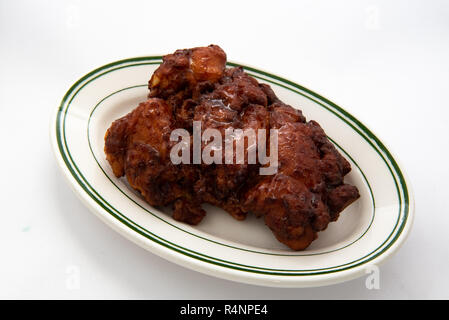 A glazed apple fritter on a white plate with a white background. Stock Photo