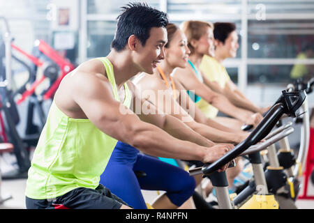 Young Asian athletes side by side in spinning class Stock Photo