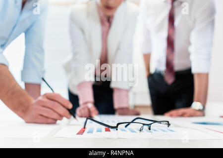 Business people analyzing data - glasses on graph Stock Photo