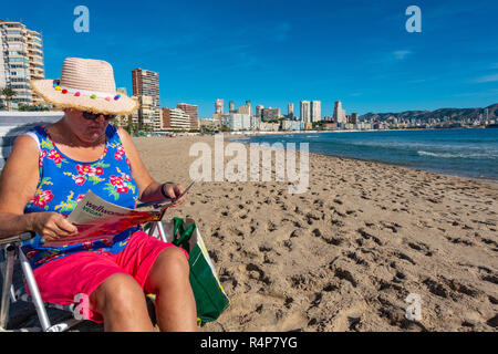 Benidorm, Costa Blanca, Spain, 28th November 2018. A Middle aged British tourist enjoys the winter sun on Poniente Beach in Benidorm as she escapes from the wet weather in the UK. Average temperatures over 17 degrees Celsius through the winter months make the Costa Blanca an ideal destination for cold and wet Brits. Credit: Mick Flynn/Alamy Live News Stock Photo