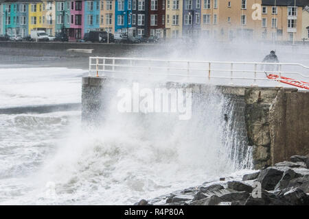 Aberystwyth Wales UK, 28th Nov 2018. UK Weather : Storm Diana, with strengthening winds gusting up to 60 or 70mph, continues to throw huge waves against the sea defences in Aberystwyth on the Cardigan Bay coast of west Wales. One foolhardy man takes a risk in getting up close to the breaking waves on the promenade.  The UK Met Office has issued a yellow warning for wind today and tomorrow for western part of the British Isles, with the risk of damage to property and likely disruption to travel.  photo credit Keith Morris / Alamy Live News Stock Photo