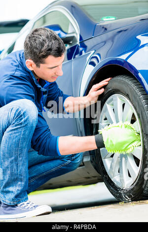 Worker using microfiber car wash mitt for cleaning rim Stock Photo