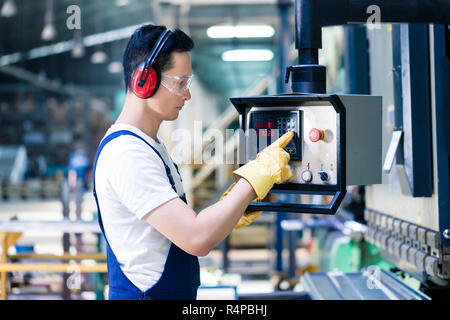 Asian worker operating CNC metal skip in factory Stock Photo