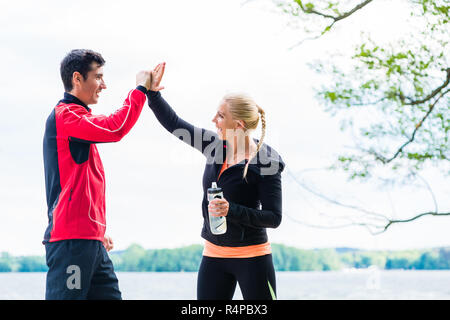 Woman and man at break from running giving each other a high five Stock Photo