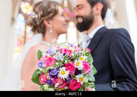 Bridal couple in church with flower bouquet Stock Photo
