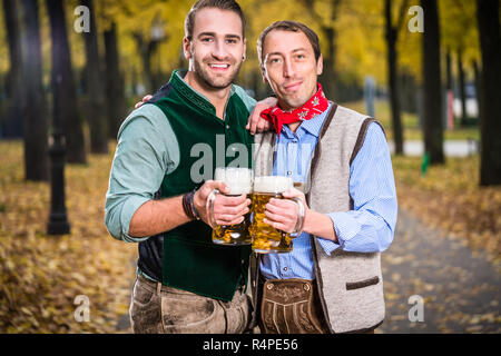 Men in bayrischer Tracht clinking glasses with beer Stock Photo