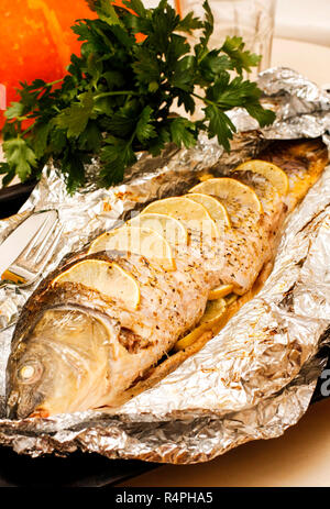 Fried carp with lemon, lime and herbs on foil Stock Photo