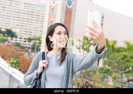 Woman taking selfie by mobile phone in Hong Kong Stock Photo